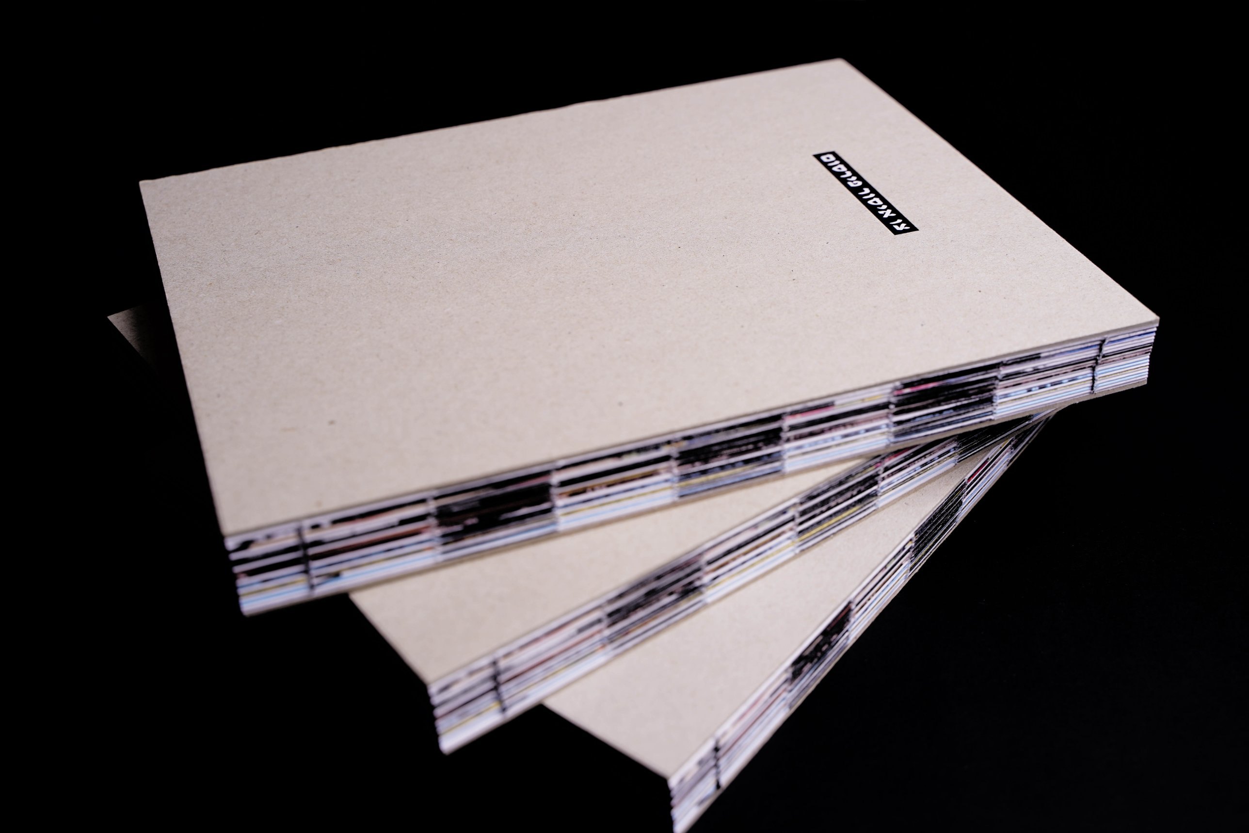 Three copies of the book stacked, showing the exposed sewn binding
